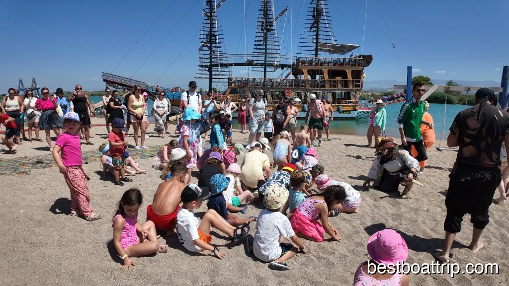 Children digging for treasure on the beach with pirate ship in background